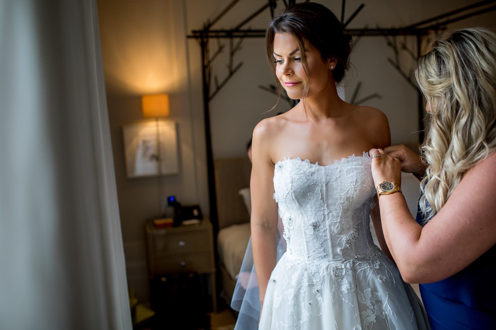 bridesmaid helping bride into dress