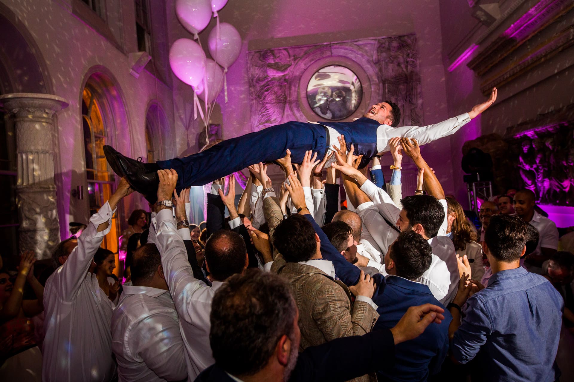 Greek groom lifted up on dance floor